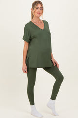 woman wearing a dark green maternity top with a v-neck and matching leggings, showcasing her baby bump