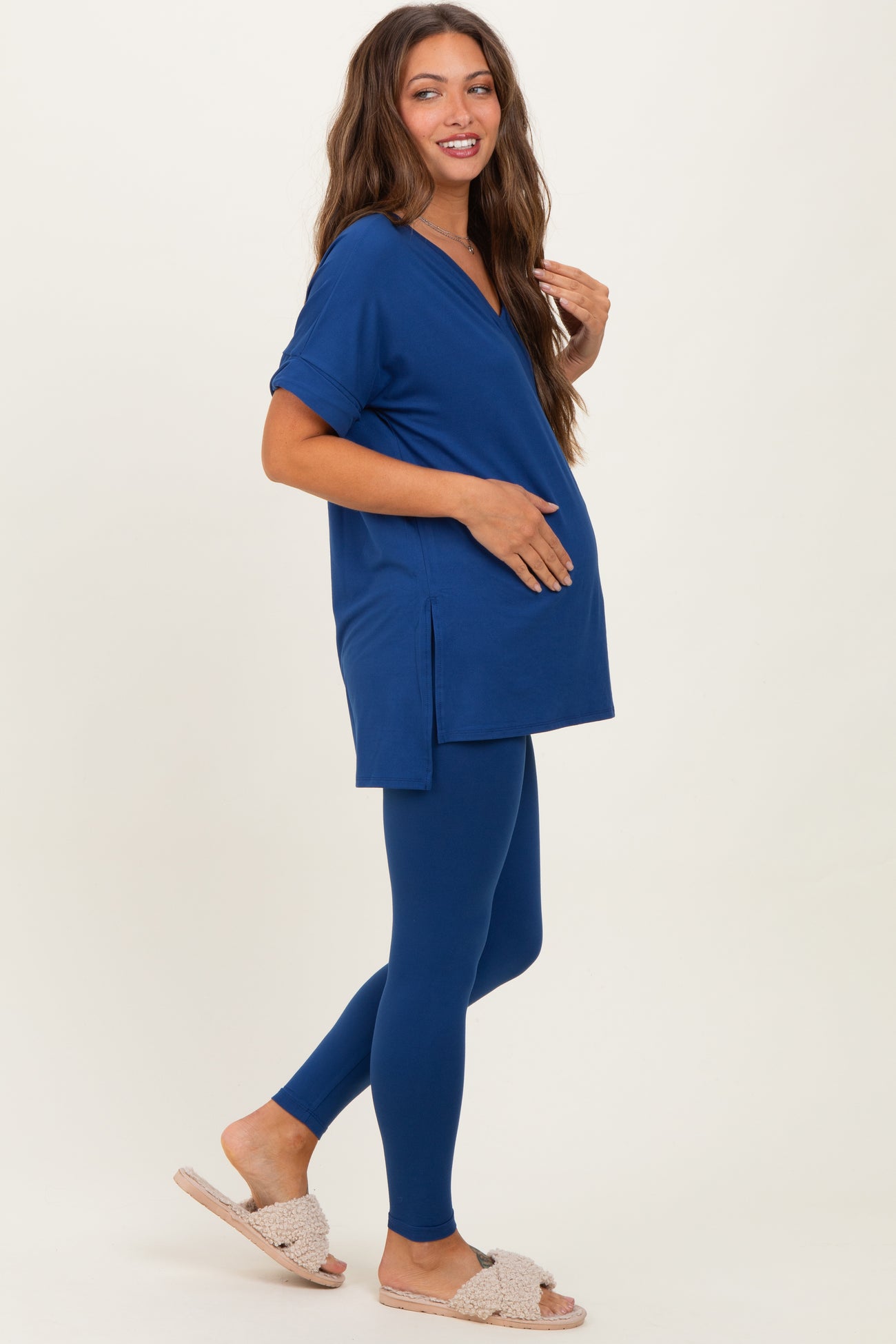 woman wearing a navy blue maternity top with side slits and matching leggings, highlighting her baby bump
