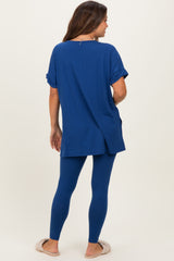 woman wearing a blue maternity top with rolled sleeves and matching leggings, showing a baby bump from the back