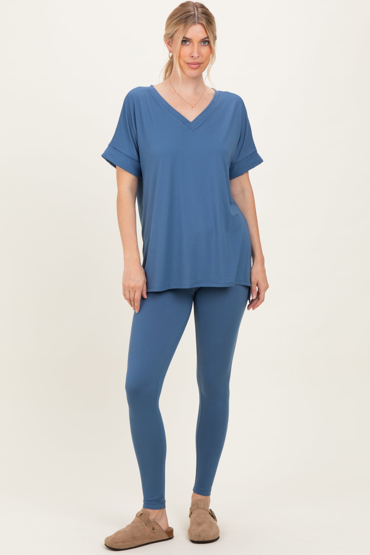 woman wearing a blue v-neck short sleeve top paired with matching leggings and slip-on shoes