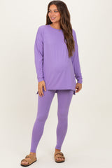 woman wearing a purple long sleeve maternity top and matching leggings, showing her baby bump