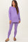 woman wearing a purple long sleeve maternity top and matching leggings, showing her baby bump