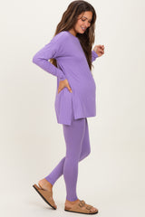 woman wearing a purple long sleeve maternity top and matching leggings, showcasing her baby bump