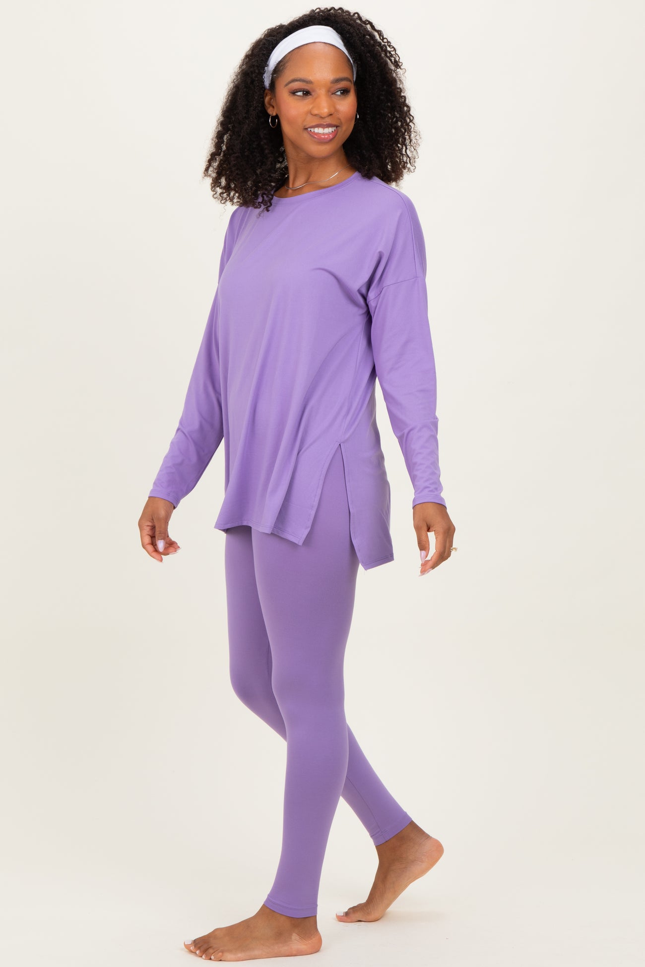 woman wearing a purple long sleeve top and matching leggings, styled for an active leisure look