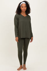 woman wearing an olive green long sleeve top and matching leggings, standing barefoot with a headband