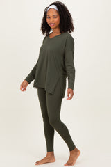 woman wearing an olive green long sleeve top with side slits and matching leggings, standing barefoot