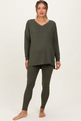 woman wearing an olive green maternity loungewear set with a v-neck long sleeve top and matching leggings, showing baby bump