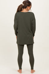 woman wearing an olive green maternity top and matching leggings, showing the back view and no visible baby bump