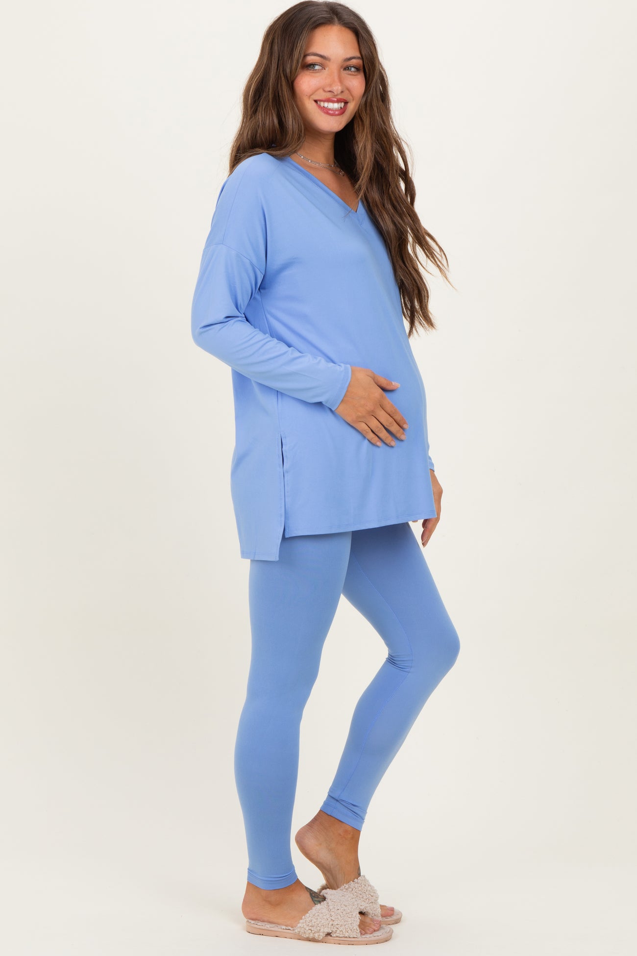 woman wearing a light blue maternity tunic and leggings, holding her baby bump