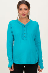 woman wearing a teal long sleeve maternity top with button details and a visible baby bump