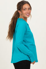 woman wearing a vibrant teal long sleeve maternity top with a round neckline and relaxed fit, showcasing her baby bump