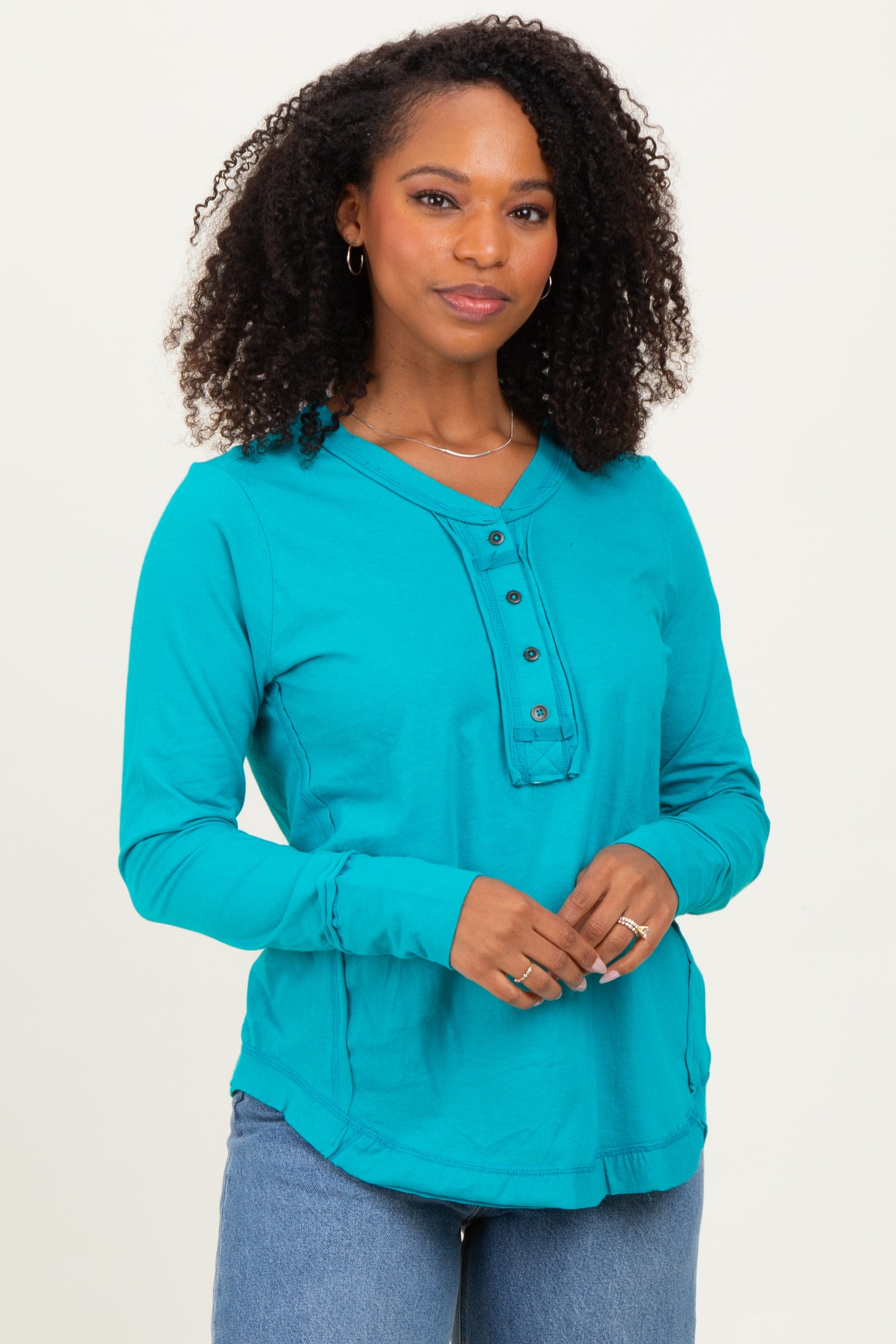 woman wearing a teal long sleeve henley top with button details and relaxed fit