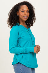 woman wearing a turquoise long sleeve henley shirt with buttons and a rounded hemline