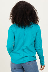 woman wearing a turquoise long sleeve top with a back seam detail and styled with blue jeans