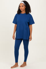 woman wearing a navy blue oversized t-shirt and matching leggings, standing barefoot against a neutral background