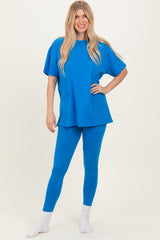 woman wearing a bright blue oversized t-shirt and matching leggings, standing with one foot slightly forward