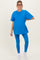 woman wearing a bright blue maternity t-shirt and matching leggings, posing with a baby bump visible