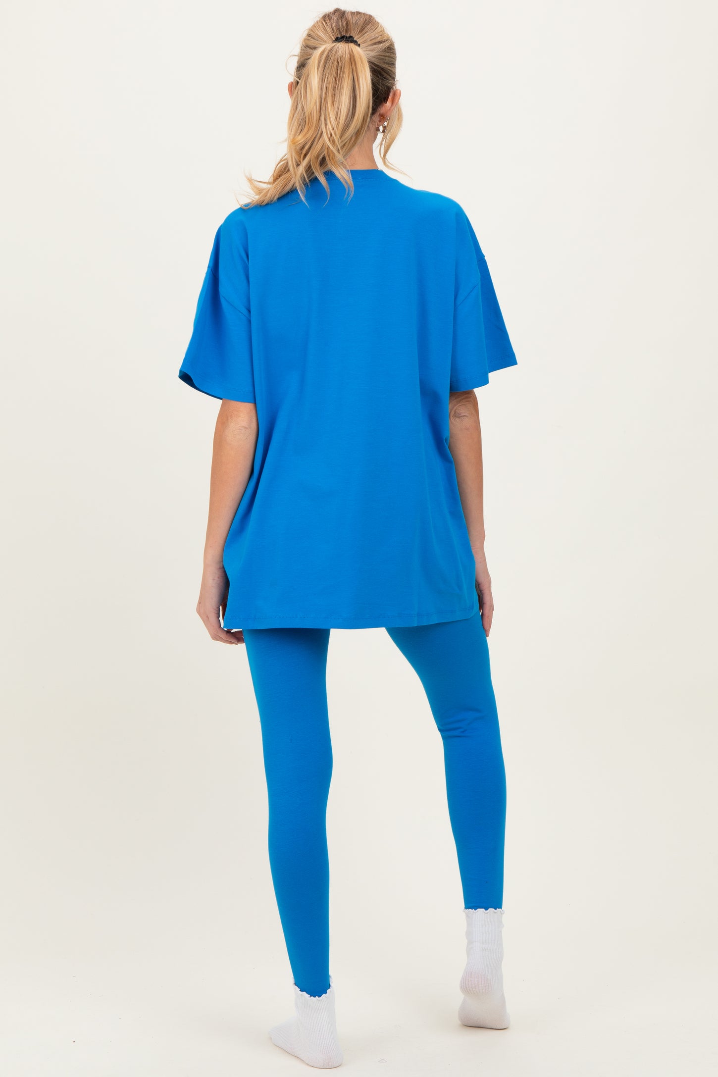 woman wearing a vibrant blue oversized maternity top and matching leggings, seen from the back
