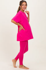woman wearing a bright pink maternity oversized t-shirt and matching leggings, showing her baby bump