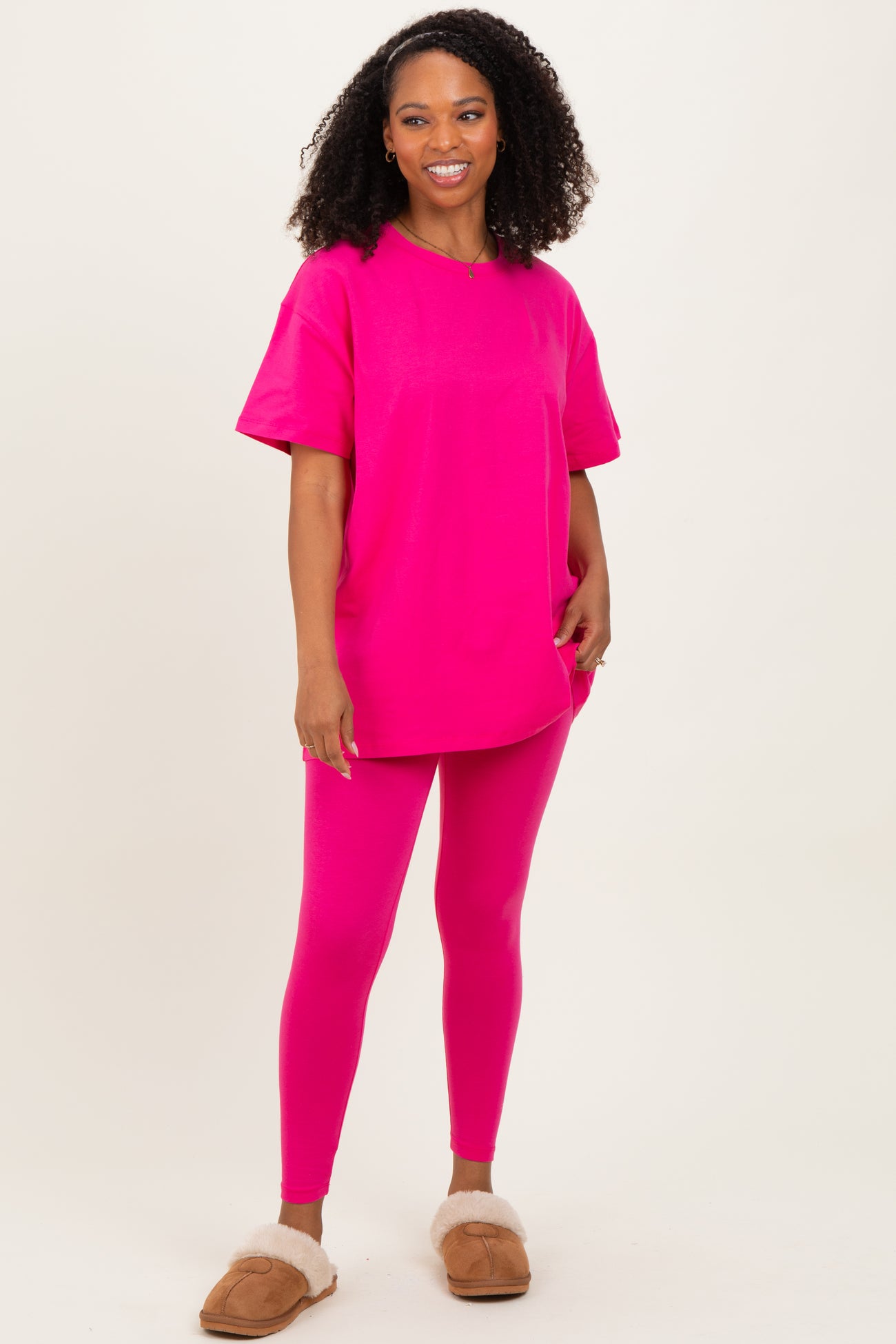 woman wearing a bright pink oversized t-shirt and matching leggings with fuzzy slippers
