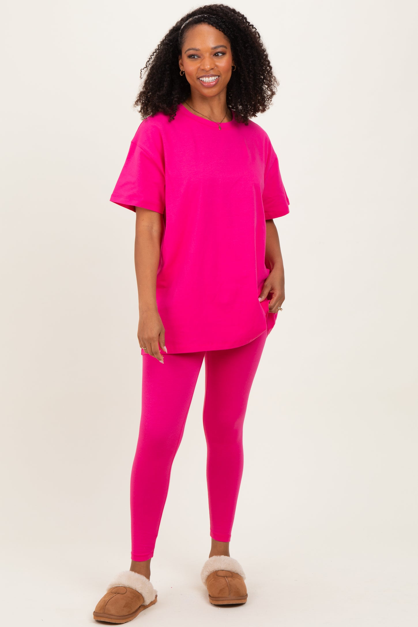 woman wearing a bright pink oversized t-shirt and matching leggings with fuzzy slippers