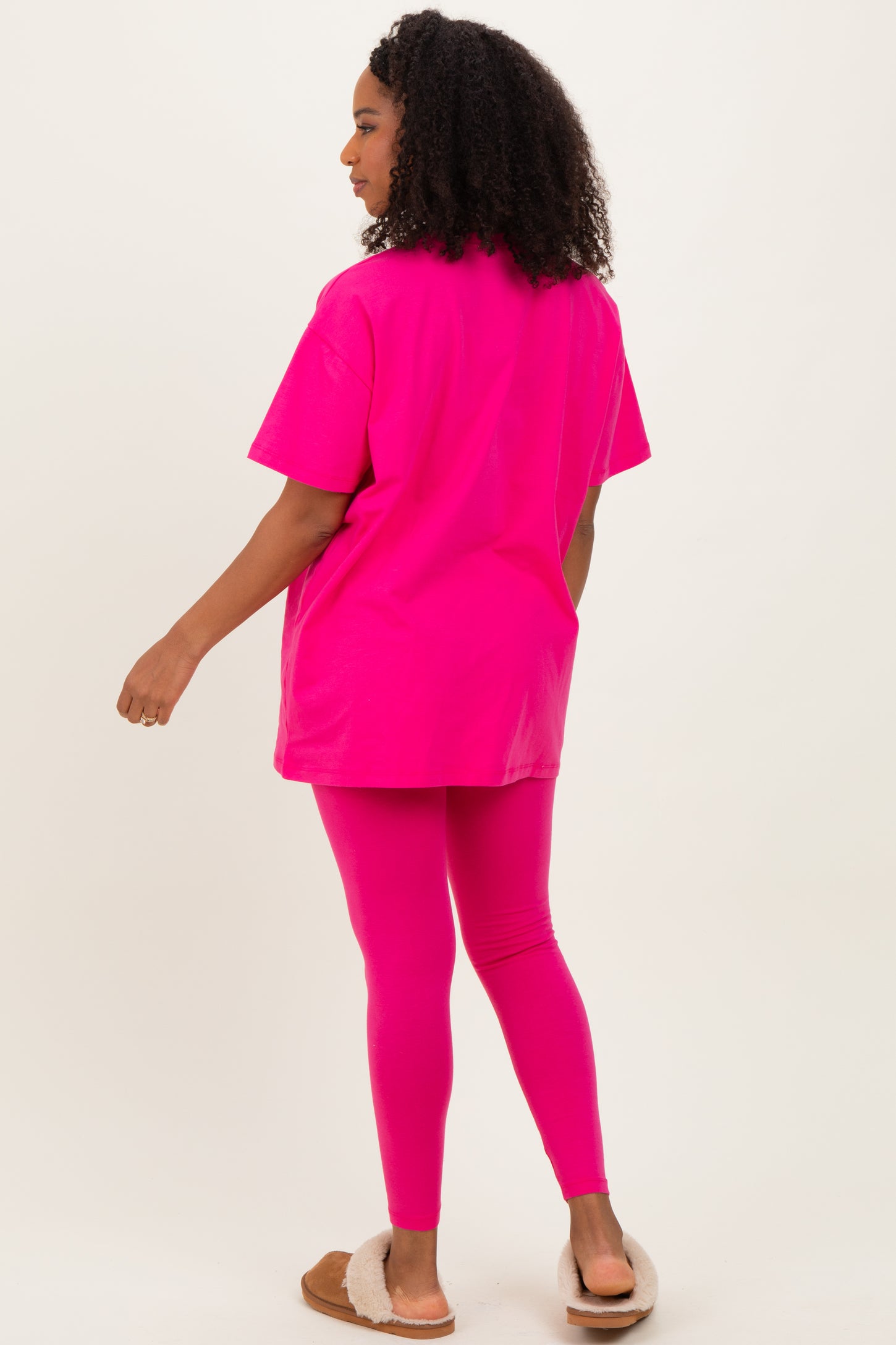 woman wearing a hot pink oversized t-shirt and matching leggings, standing with her back to the camera