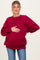 woman wearing a burgundy oversized maternity sweatshirt and holding her baby bump