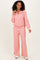 woman wearing a light pink two-piece lounge set with a zip-up hoodie and wide-leg pants