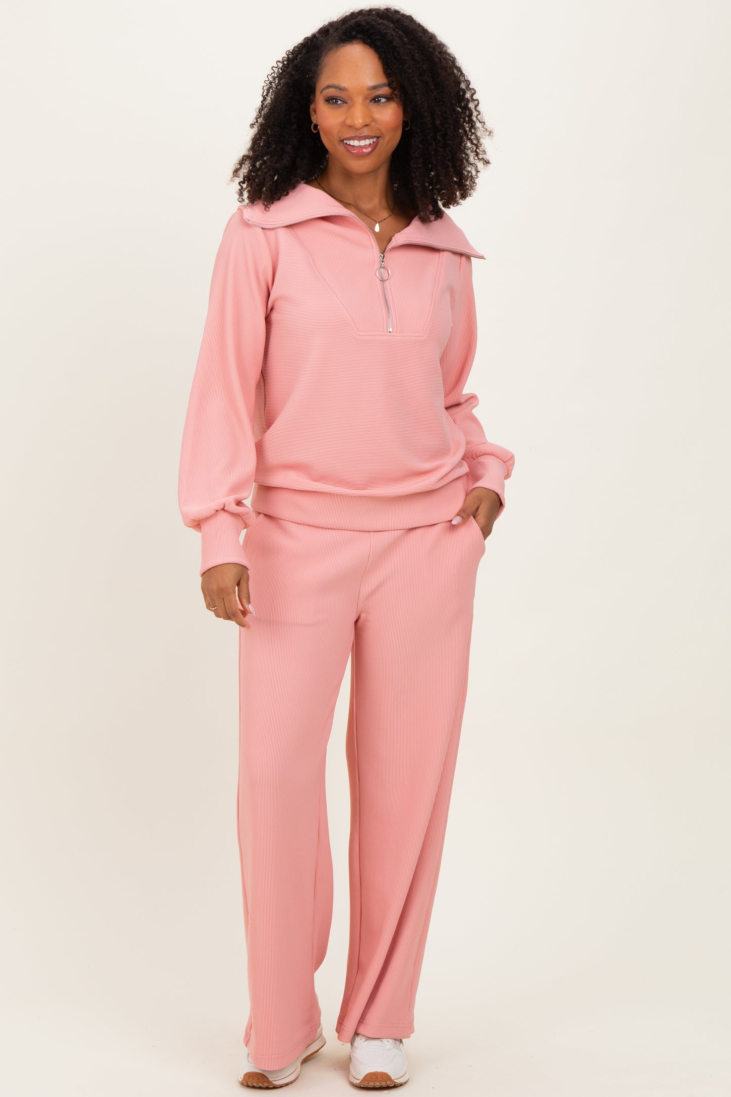 woman wearing a soft pink long sleeve zip-up top and matching wide-leg pants, styled in a relaxed fit