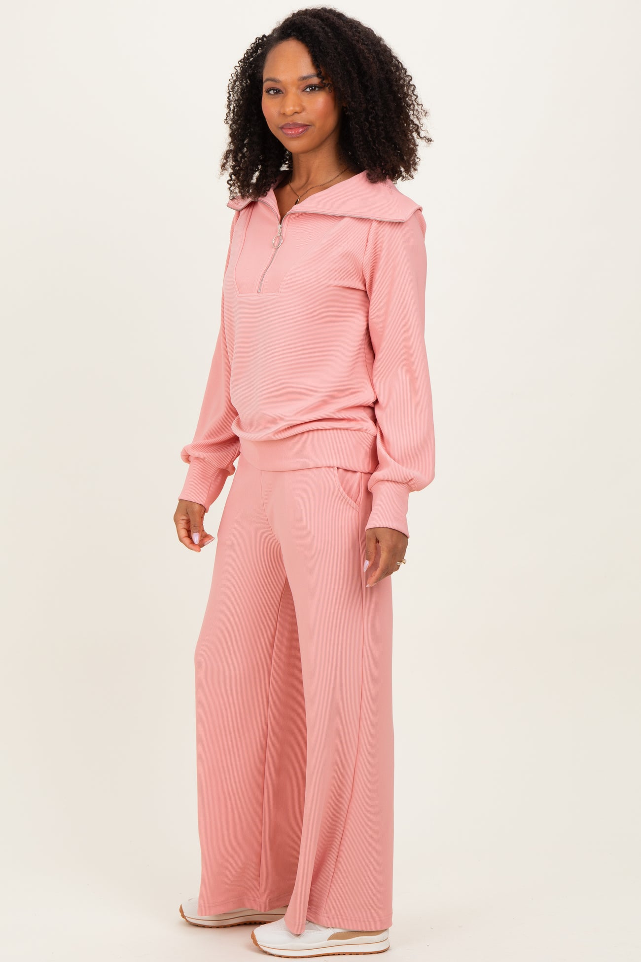 woman wearing a light pink ribbed zip-up pullover and matching wide-leg pants