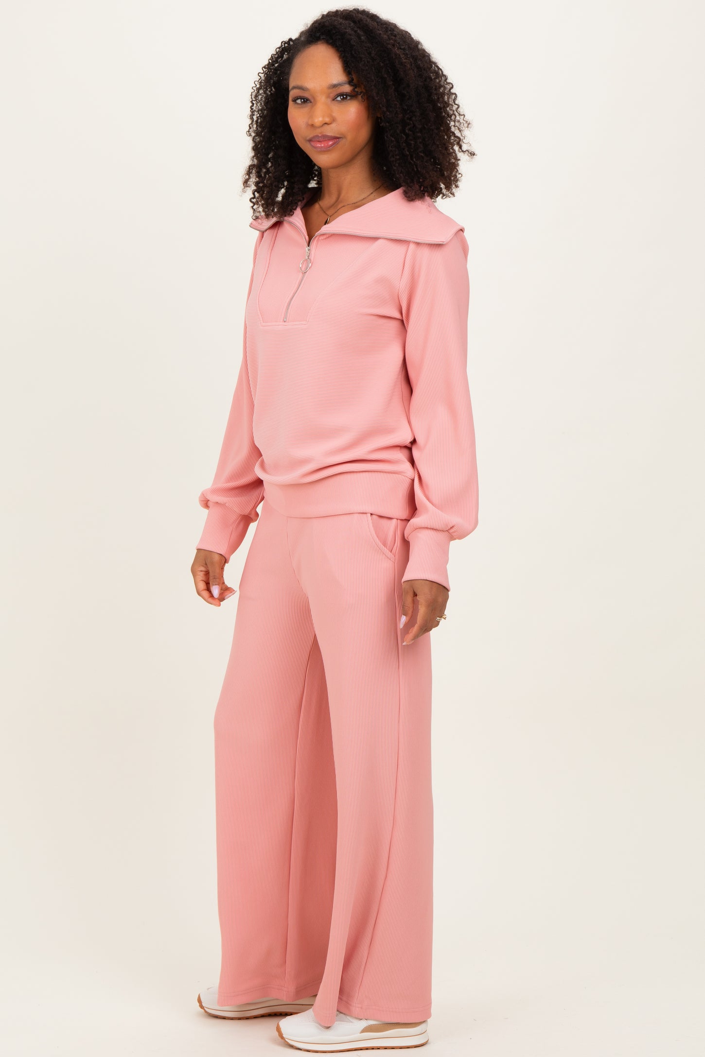 woman wearing a light pink ribbed zip-up pullover and matching wide-leg pants