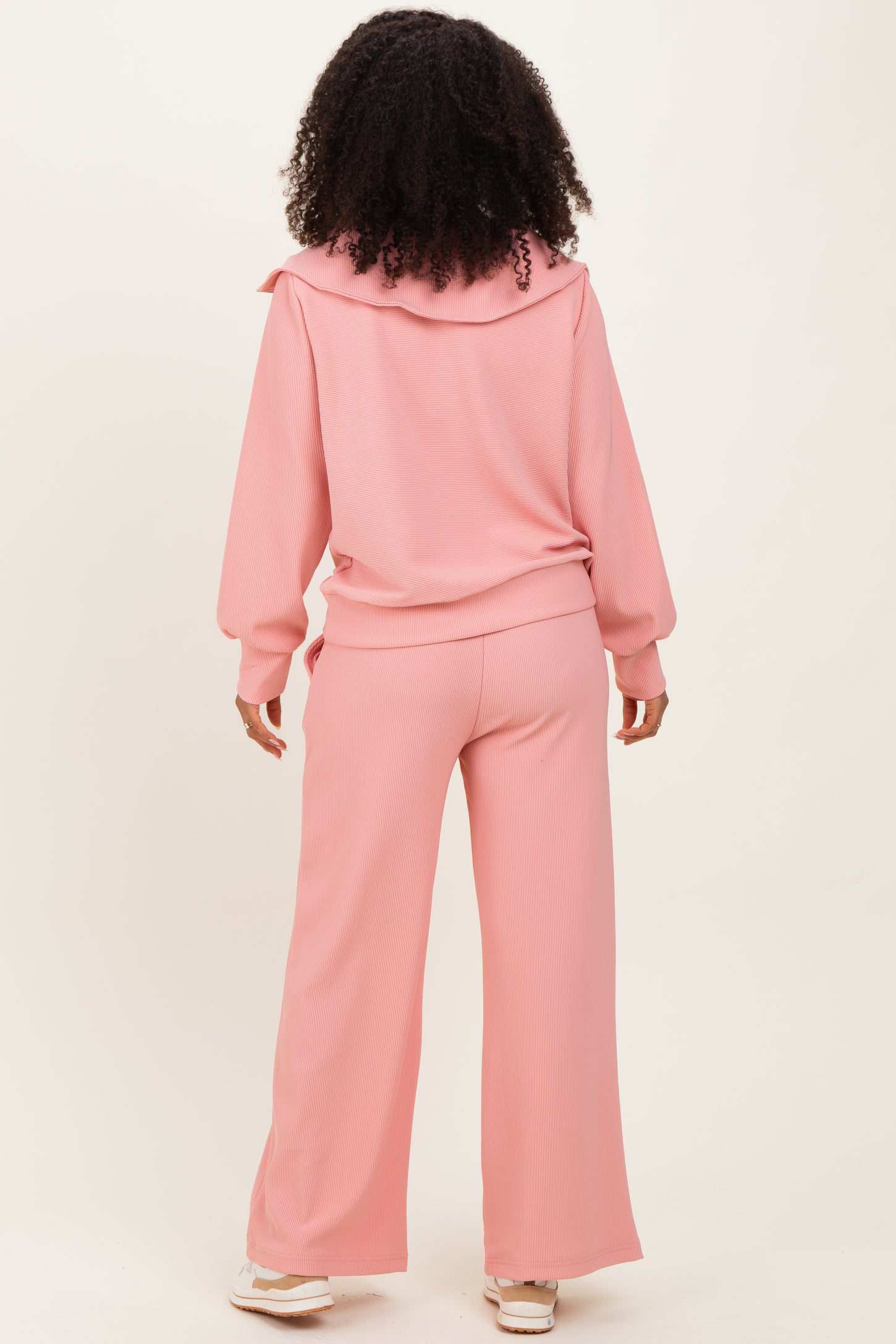woman wearing a pink ribbed loungewear set with a hoodie and wide-leg pants, shown from the back