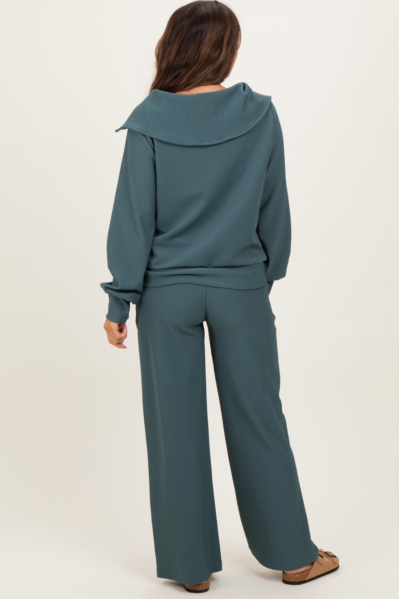 woman wearing a teal maternity loungewear set with a wide collar top and matching pants, showcasing a relaxed fit.