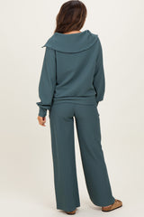 woman wearing a teal maternity loungewear set with a wide collar top and matching pants, showcasing a relaxed fit.