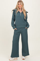 woman wearing a teal ribbed zip-up long sleeve top and wide leg pants, styled for a casual look