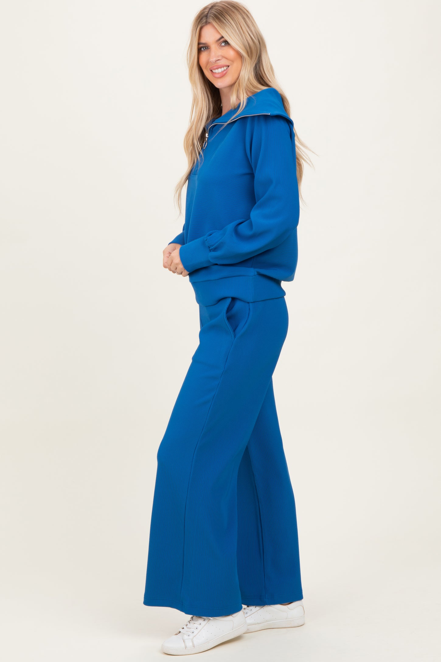 woman wearing a bright blue ribbed hoodie and matching wide-leg pants, styled with white sneakers