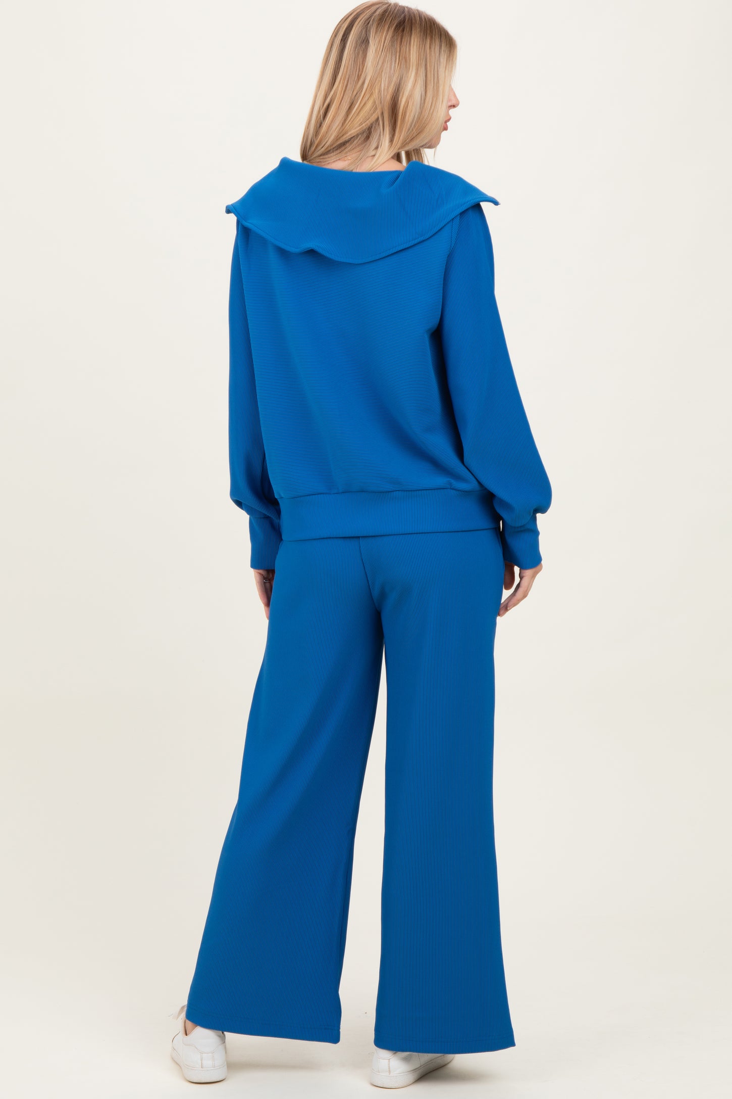 woman wearing a blue ribbed tracksuit with a hooded top and wide-leg pants, viewed from the back