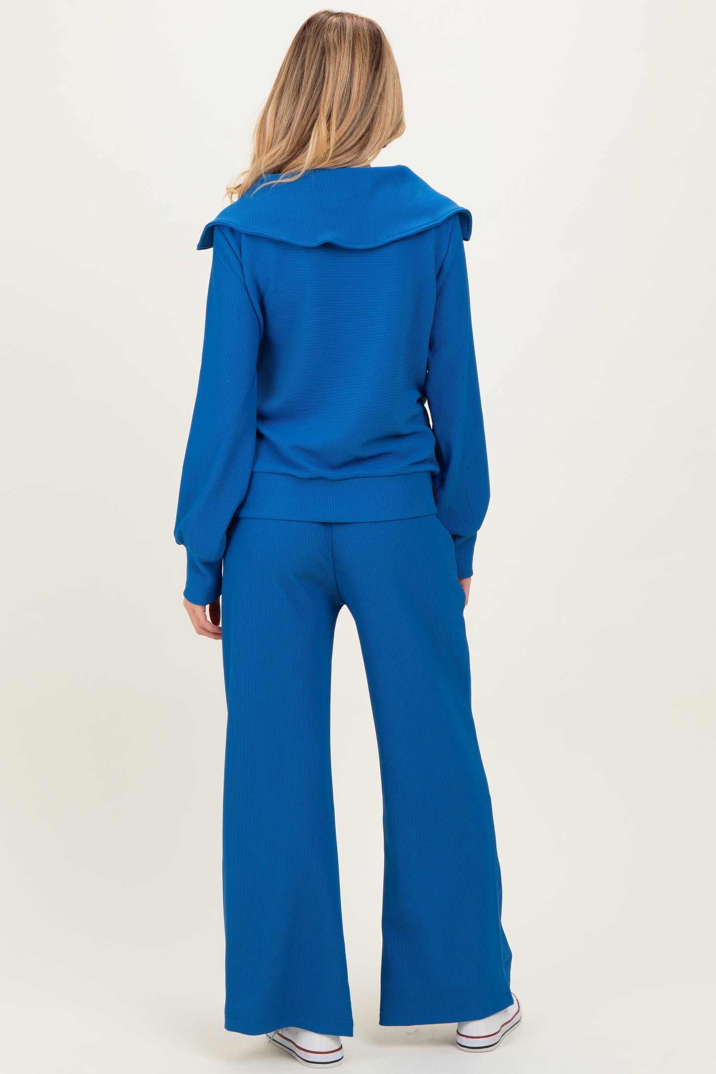 woman wearing a blue maternity top with a large collar and matching wide-legged pants, back view