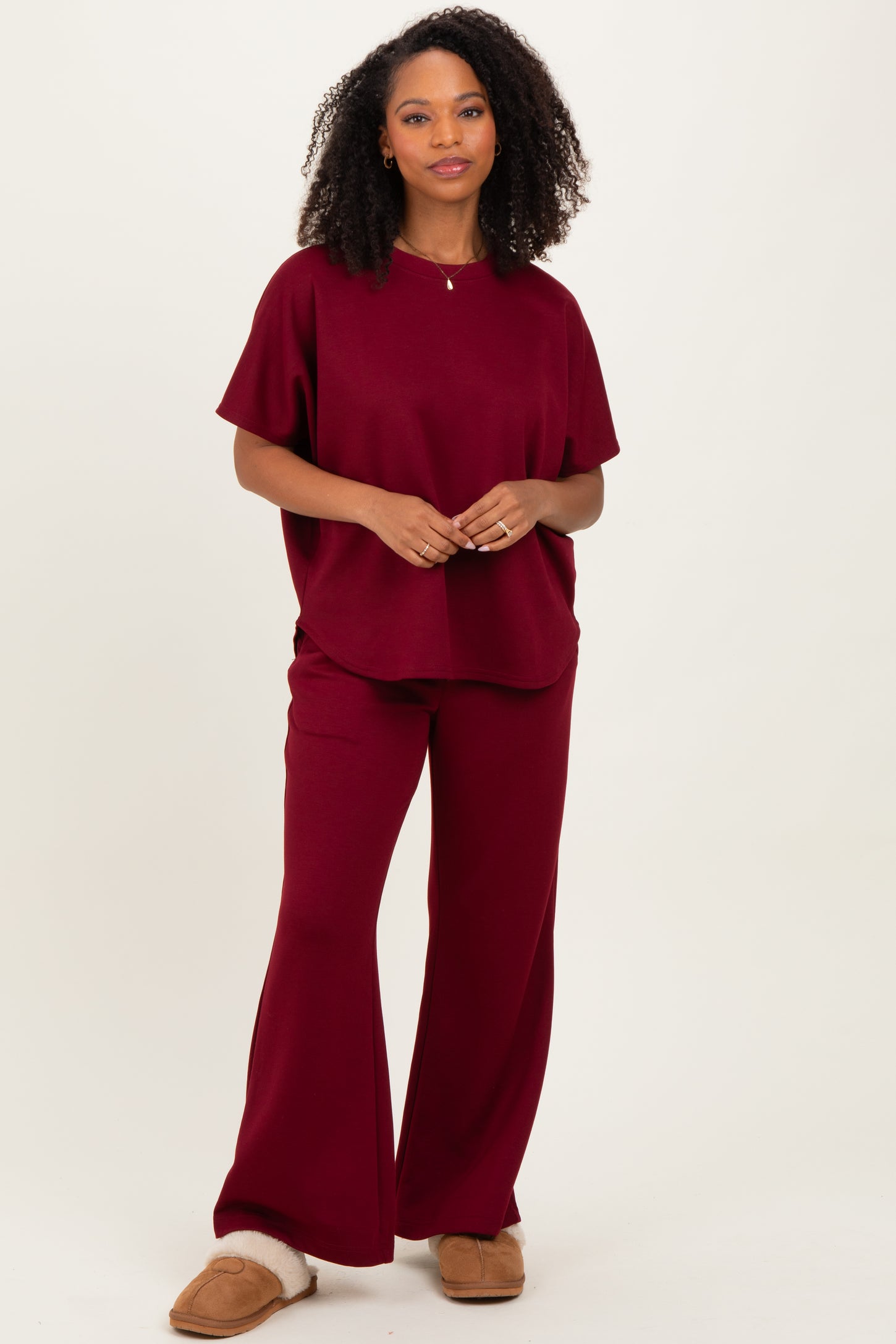 woman wearing a burgundy oversized t-shirt and matching wide-leg pants with cozy slippers