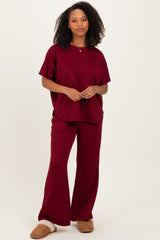 woman wearing a burgundy oversized t-shirt and matching wide-leg pants with cozy slippers