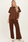 woman wearing a brown oversized t-shirt and matching wide-leg pants, styled with white sneakers