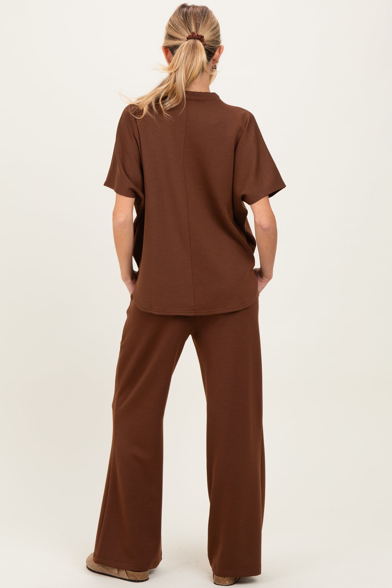 woman wearing a brown maternity lounge set, featuring a short sleeve top and wide-leg pants, viewed from the back
