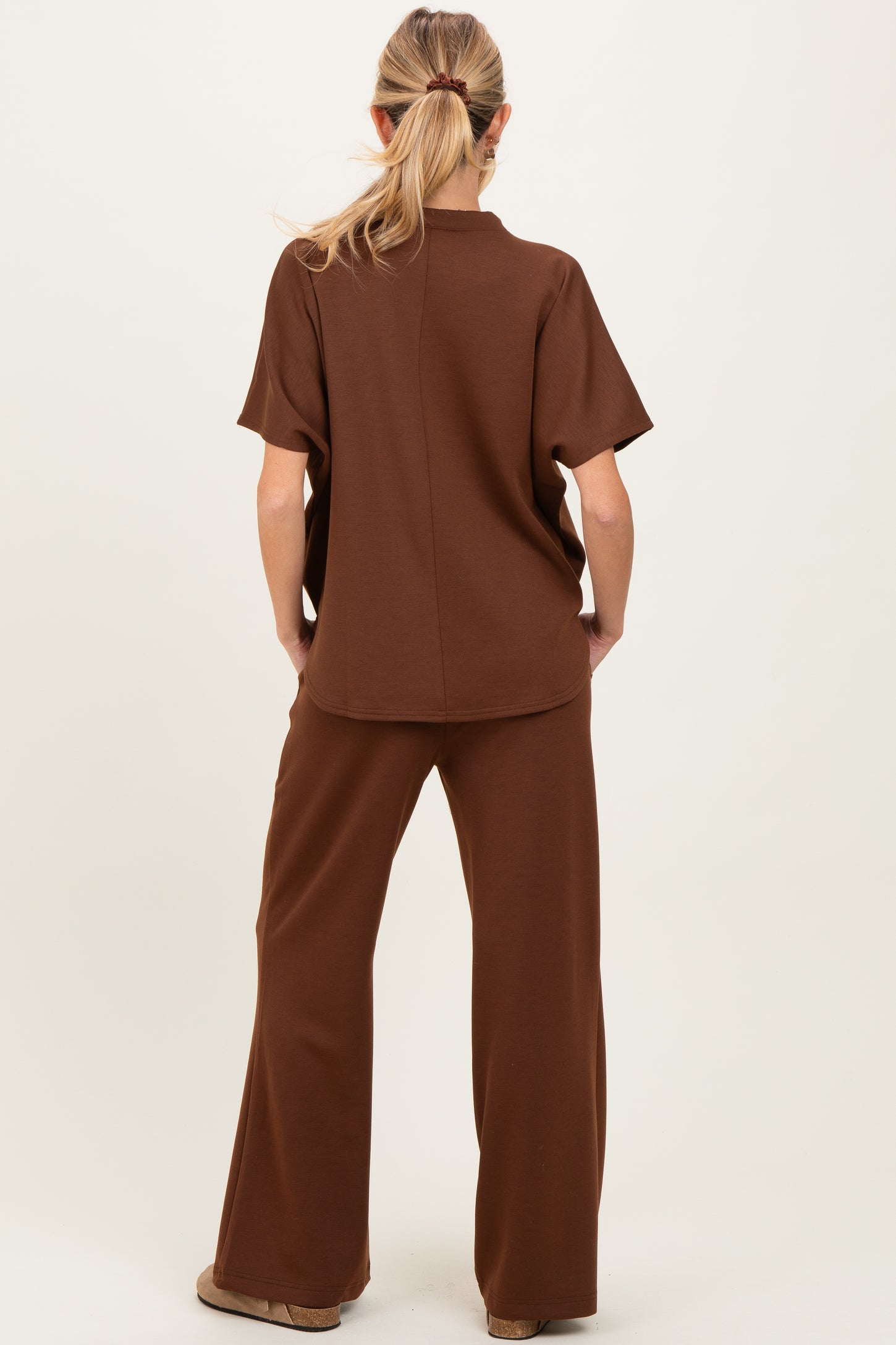 woman wearing a brown maternity lounge set, featuring a short sleeve top and wide-leg pants, viewed from the back