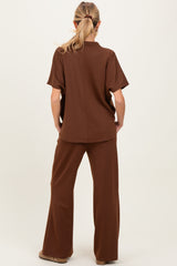woman wearing a brown maternity lounge set, featuring a short sleeve top and wide-leg pants, viewed from the back