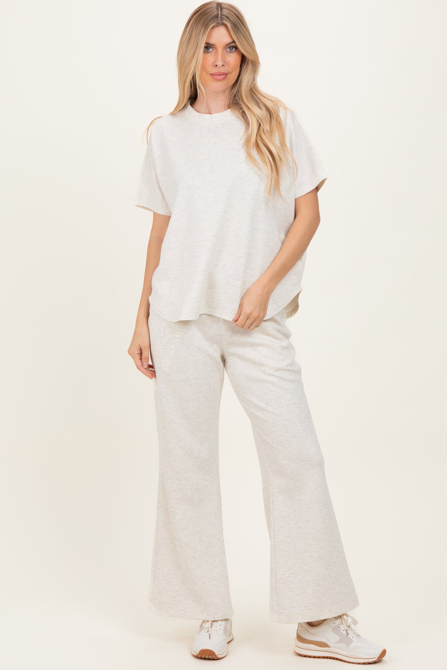 woman wearing a light grey relaxed fit top and matching wide leg pants with sneakers