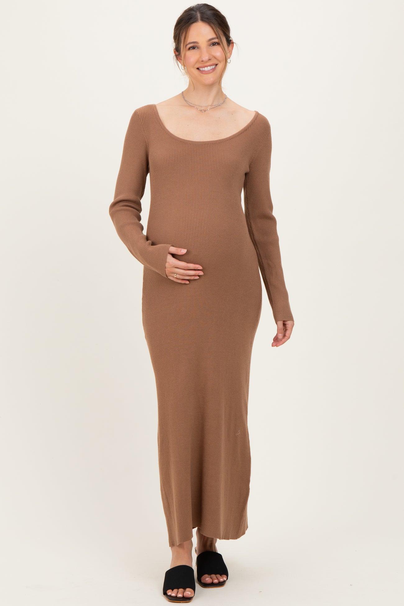 woman wearing a brown ribbed maternity dress with long sleeves and holding her baby bump