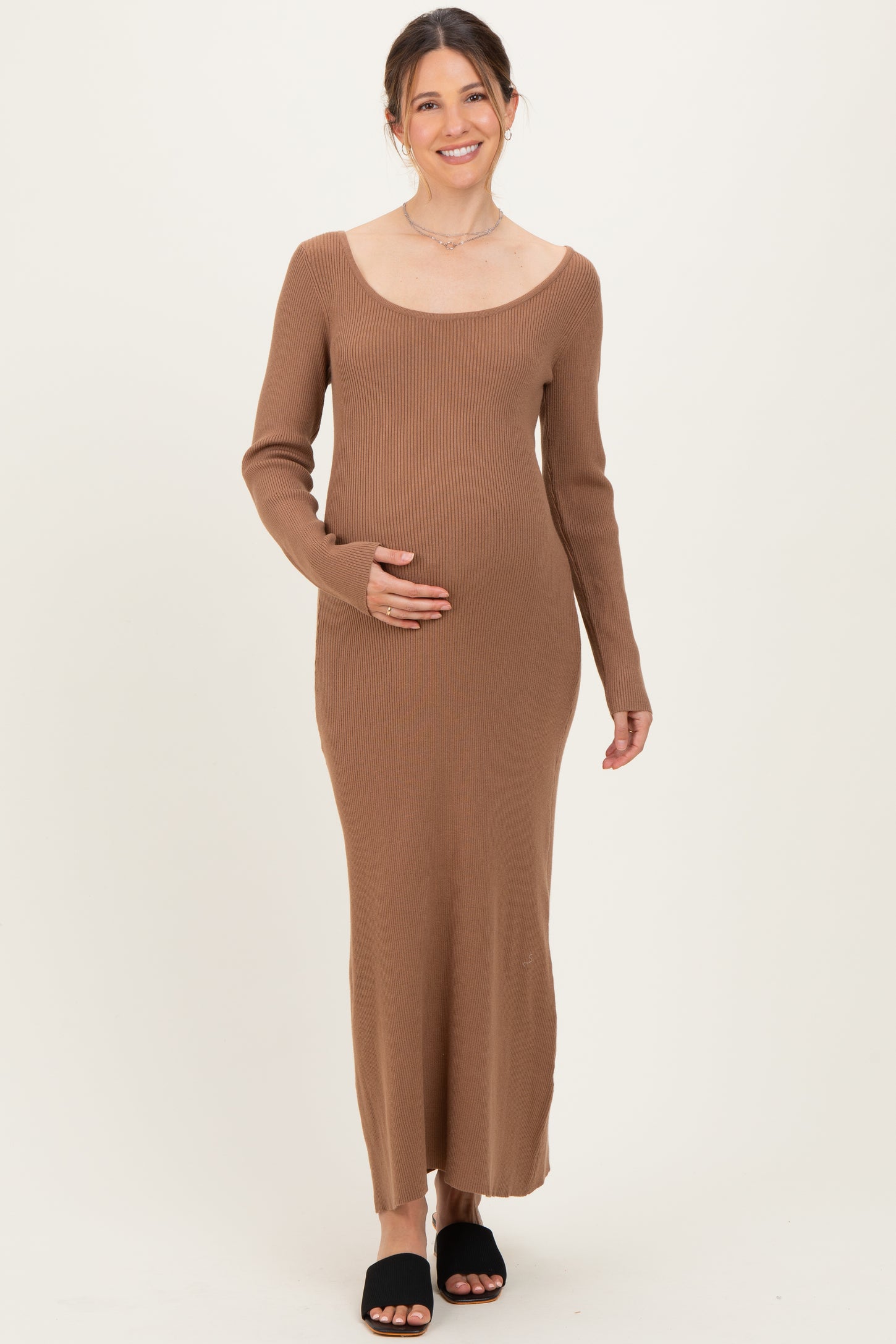 woman wearing a brown ribbed maternity dress with long sleeves and holding her baby bump