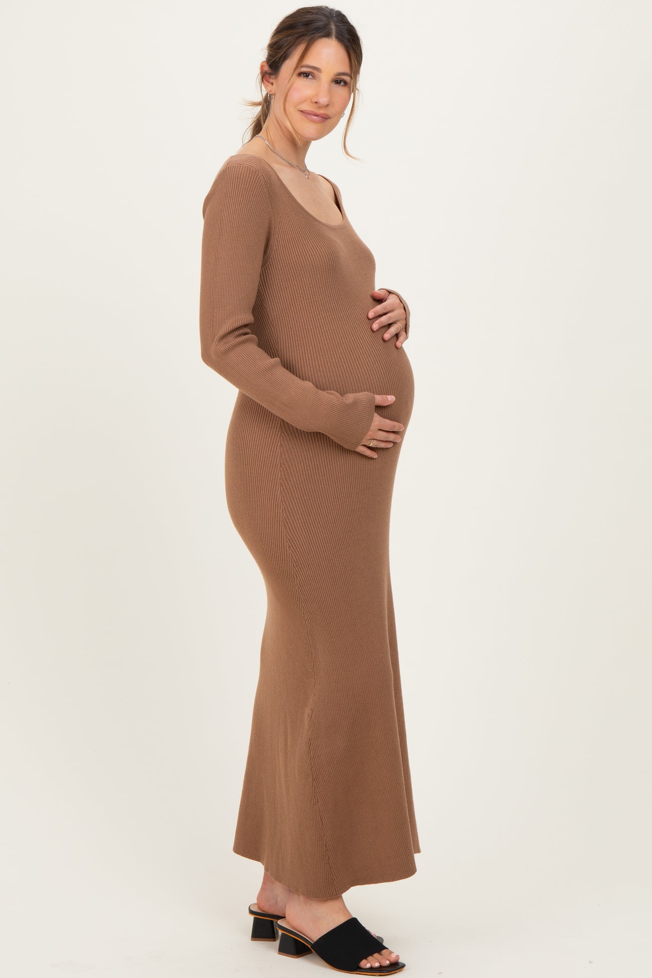 woman wearing a brown ribbed maternity maxi dress and holding her baby bump