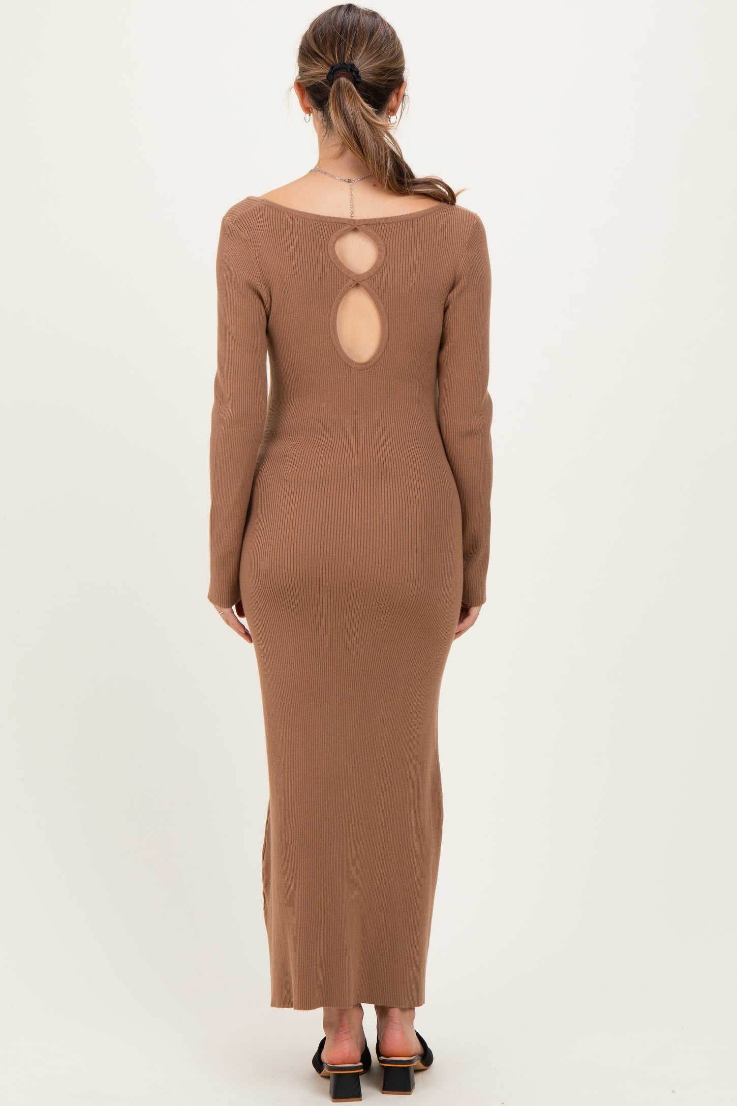 woman wearing a brown ribbed maternity dress with a keyhole back detail and long sleeves
