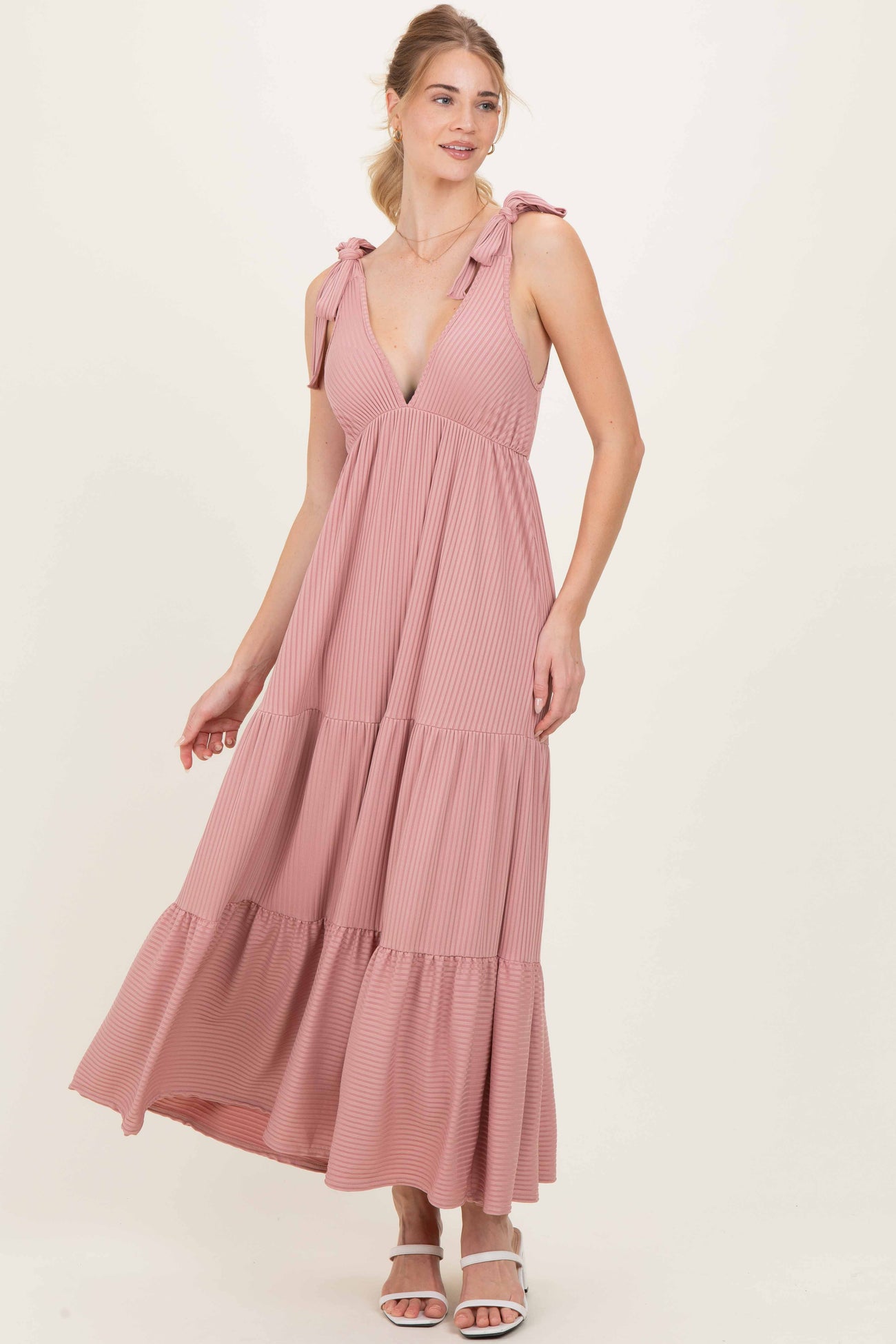 woman wearing a pink striped maxi dress with tie shoulder straps and a tiered skirt